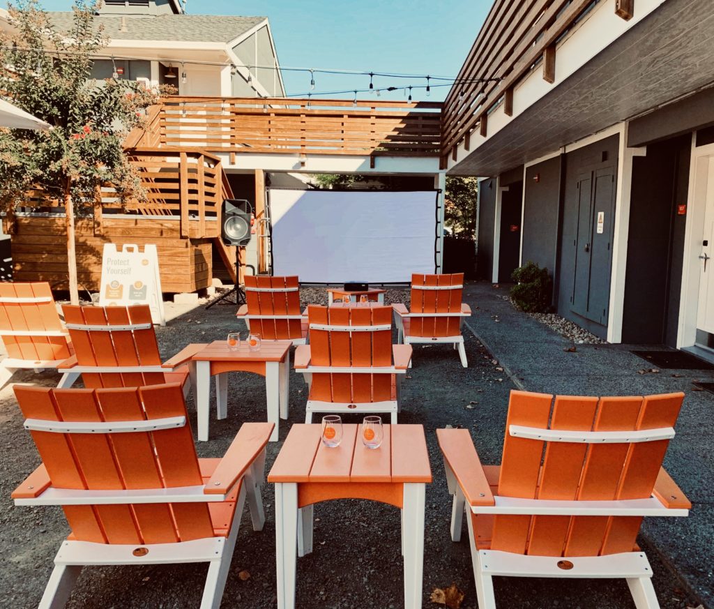 Lawn chairs spaced in the UpValley Inn courtyard face a projector screen for Movie Night Inn.